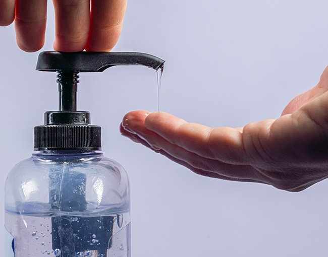 A hand getting hand sanitzer from a bottle