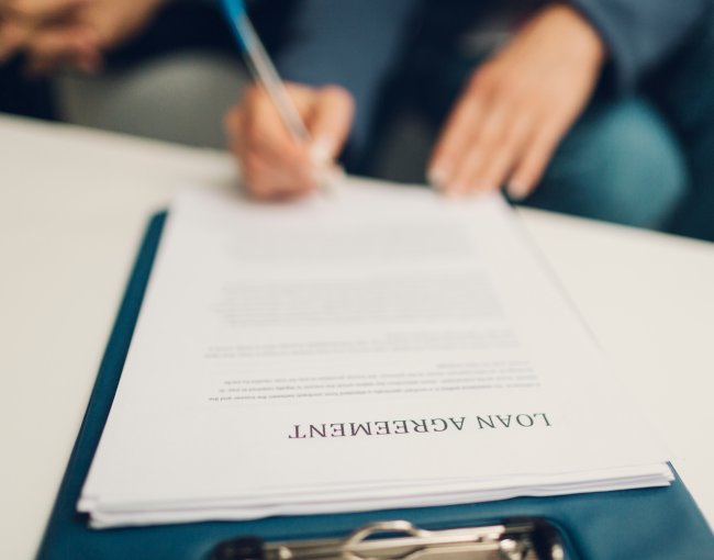 Blurred photo of someone signing a loan agreement