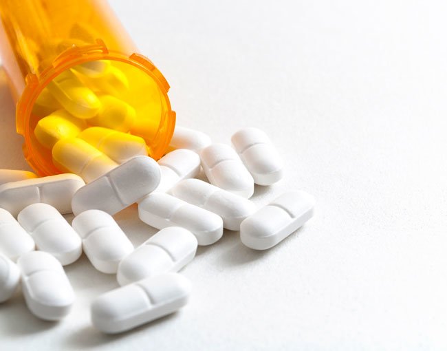 An open pill bottle spilling prescription pain medicine