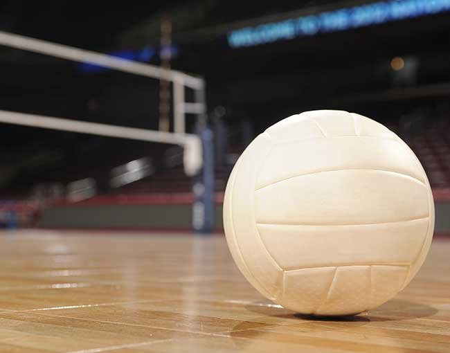 Volleyball sitting on court floor with net in background